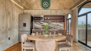 Une cuisine moderne avec un revêtement mural en marbre, un four à micro-ondes encastré et un coin repas comprenant une table ronde et des chaises rembourrées.