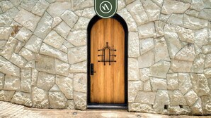 Un mur de pierre avec une porte en bois, dotée d’une poignée en métal et d’un logo.