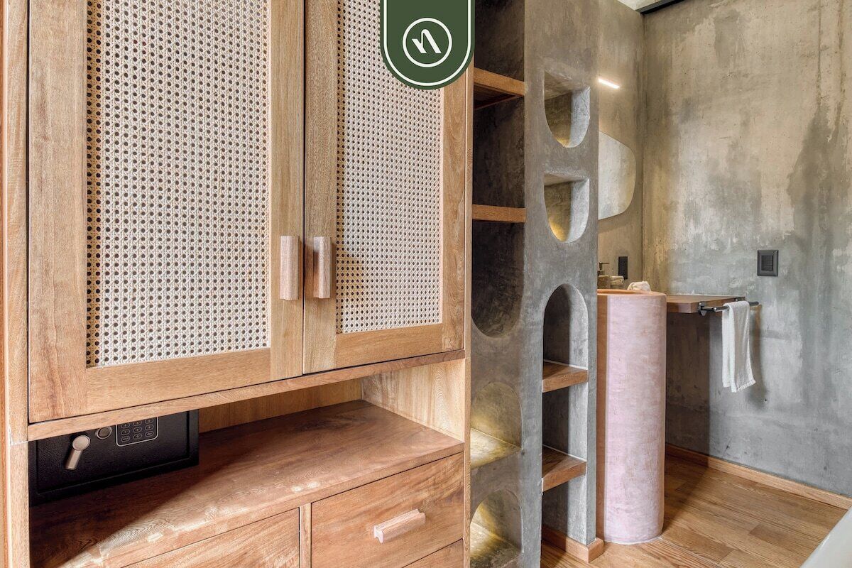 A modern bathroom with wooden cabinetry, a large mirror, and a concrete accent wall.