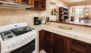 Eine Küche mit Herd, Backofen, Kaffeemaschine und einem Essbereich mit Tisch und Stühlen.