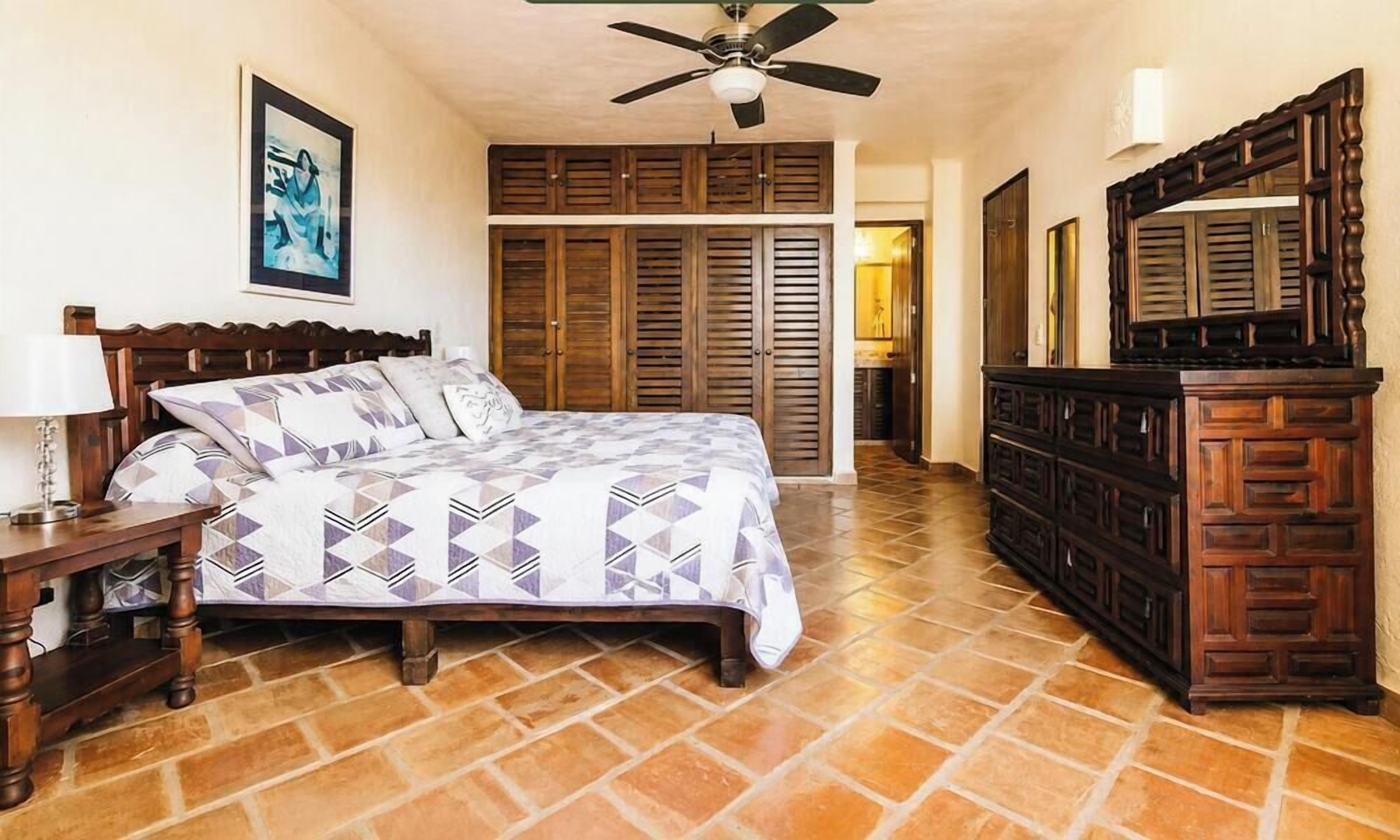 Un dormitorio con cama, armario de madera y ventilador de techo.
