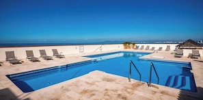 A rectangular pool with a clear blue sky and distant mountains in the background.