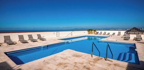 Ein Dachpool mit Liegestühlen und freiem Blick auf den Ozean.