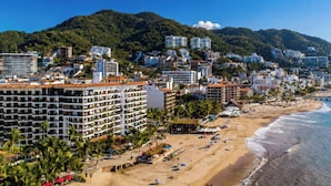 Eine Küstenstadt mit Strand, Hotels und einem Bergpanorama.