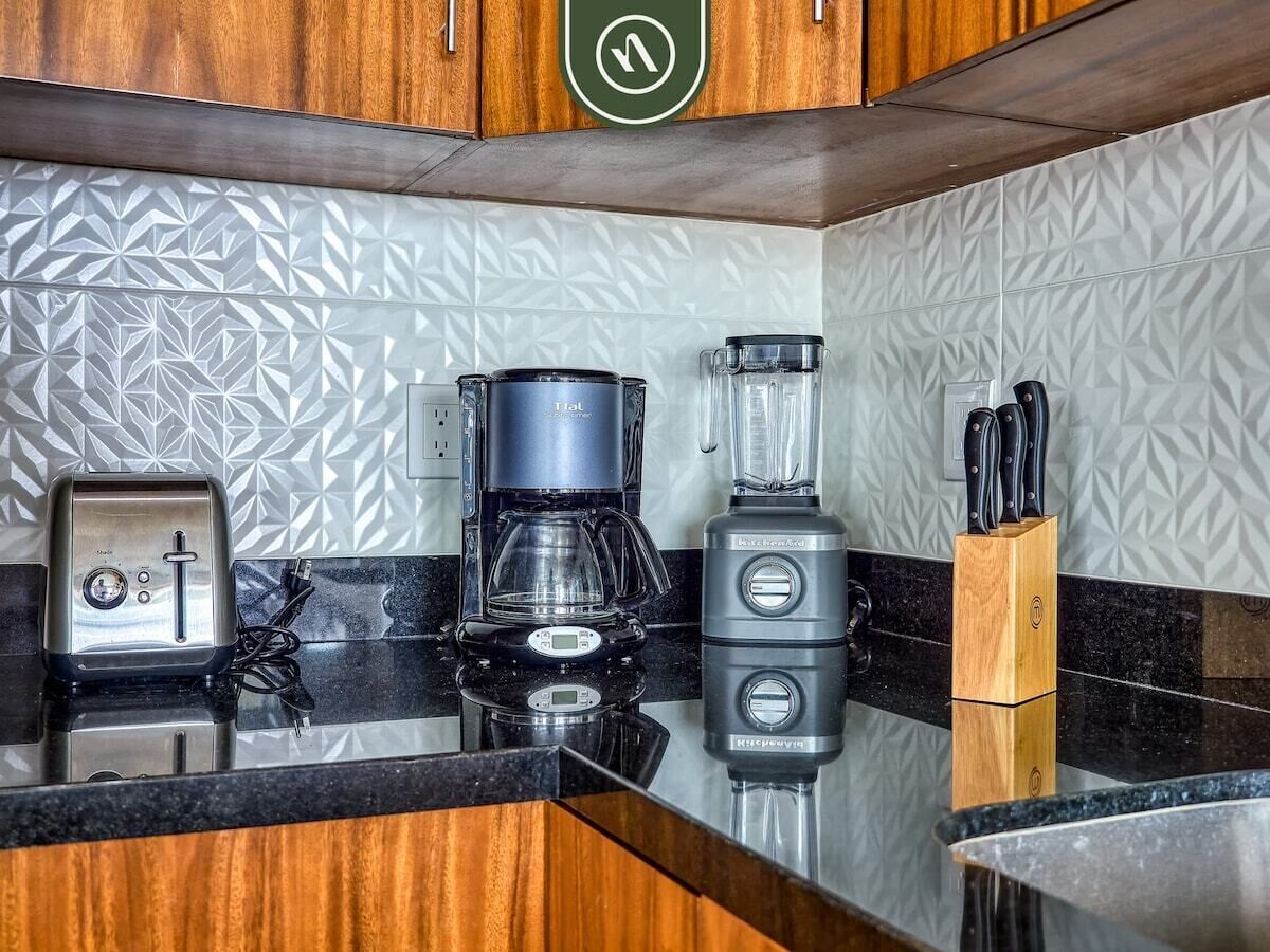 A kitchen with a coffee maker, blender, and toaster on a black countertop.