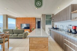 Una cocina moderna con una isla central, armarios de madera y un televisor de pantalla plana.