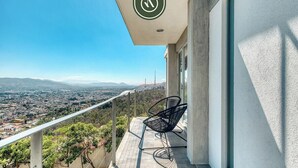 Un balcón con vistas a un paisaje urbano y montañas.