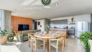 Un espacio habitable moderno con comedor, cocina y zona de entretenimiento.