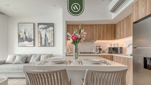 A modern kitchen with wooden cabinets, a central island with seating, and a dining area with a white table and chairs. - Oceanview 1 BR Condo With Pools and Beach Access (Puerto Vallarta)