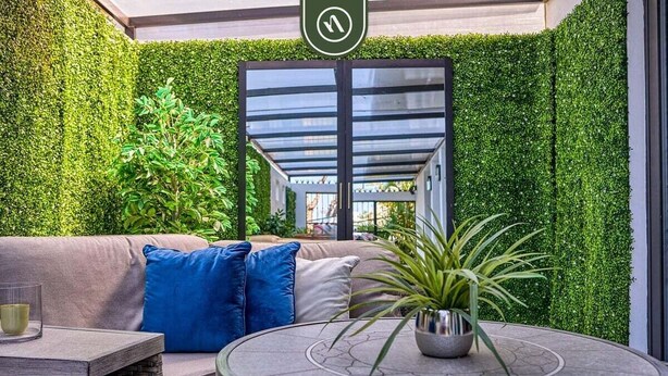 A modern outdoor seating area with a cushioned bench, a round table, and a potted plant. - Modern 2BR Condo in Old Town - Private Terrace (Puerto Vallarta)