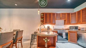 A modern kitchen with wooden cabinets, a central island, and a dining area with chairs. - Modern 2BR Condo in Old Town - Private Terrace (Puerto Vallarta)