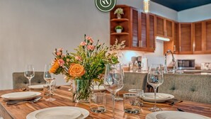 A dining table set for four with white plates, cutlery, and wine glasses, a centerpiece of flowers, and wooden cabinets in the background. - Modern 2BR Condo in Old Town - Private Terrace (Puerto Vallarta)