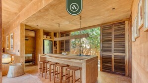 A wooden interior with a central island, bar stools, and a hanging light fixture. - Stunning Two-bedroom Ocean View House - Mazul (Santa María Tonameca)