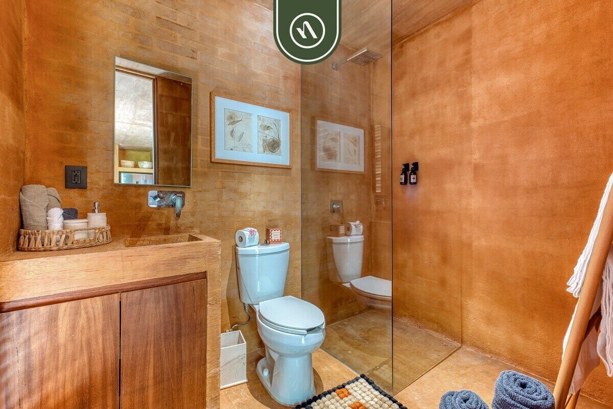 A bathroom with a wooden vanity, a toilet, and a shower area.