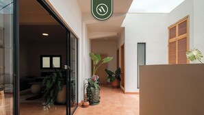A hallway with potted plants, a reception desk, and a sign with a symbol. - Centric 3BR Condo in Downtown in Oaxaca (Oaxaca)
