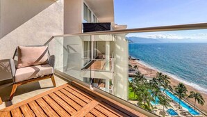 Un balcon avec vue sur la plage et l’océan, une chaise et un espace piscine.