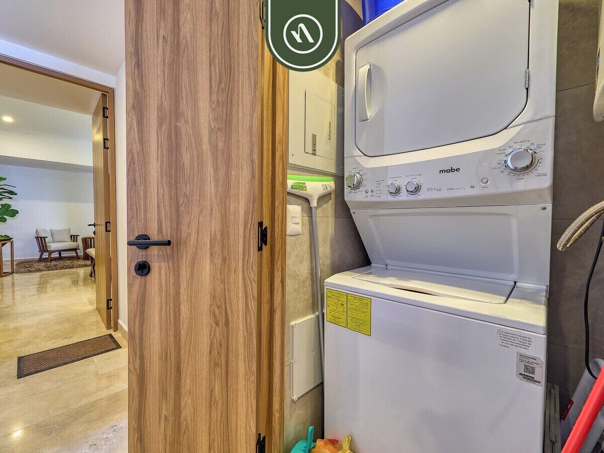 Une buanderie équipée d’un lave-linge et d’un sèche-linge, avec une porte en bois et une prise électrique visible.