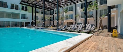 A swimming pool with lounge chairs and a wooden deck area.