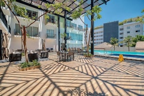 Un espace extérieur avec une piscine, des chaises longues, une table et une structure en forme de pergola.