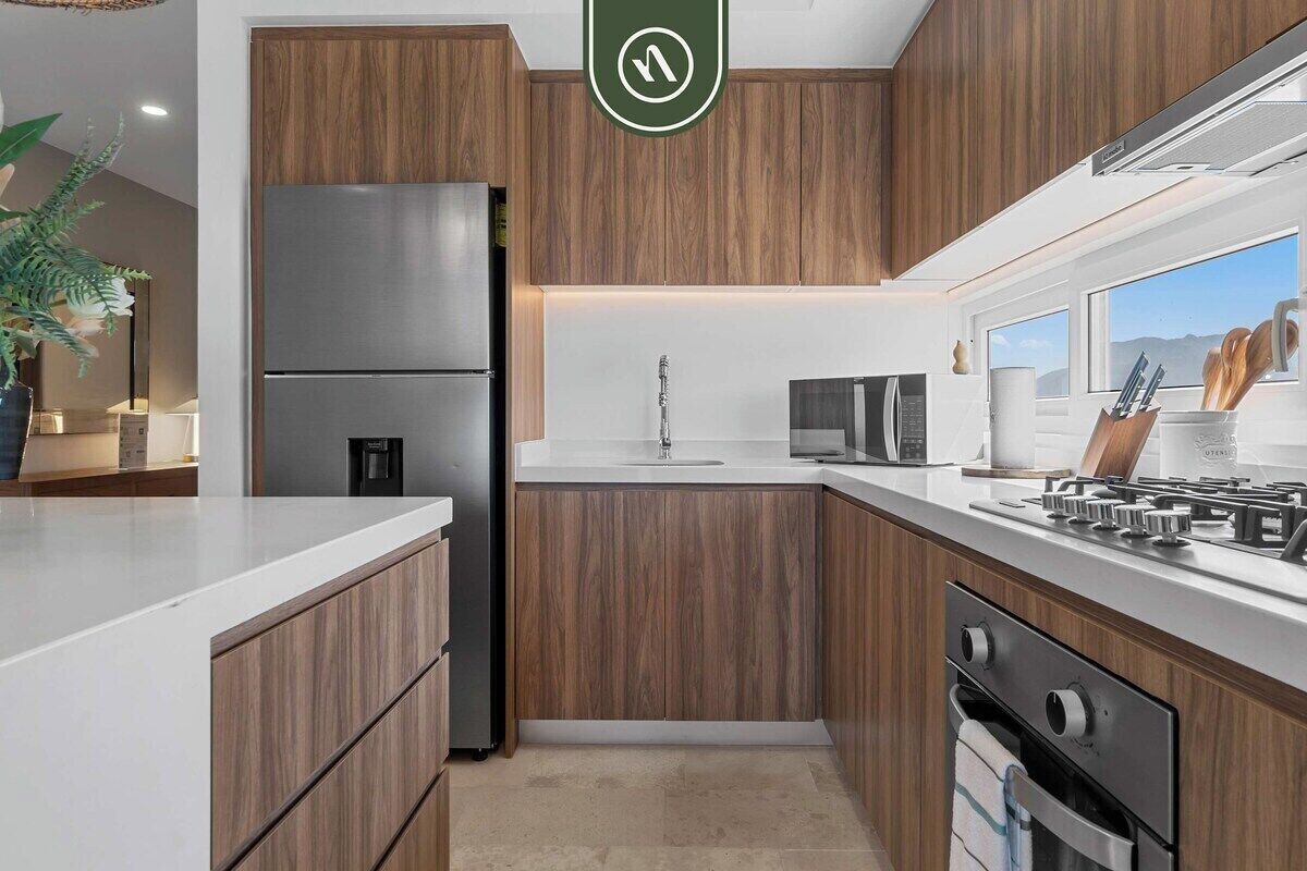 A modern kitchen with wooden cabinets, a stainless steel refrigerator, a gas stove, and a built-in oven.