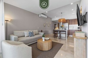 A modern living room with a sofa, coffee table, and a dining area with chairs and a table.
