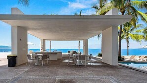 A covered outdoor area with tables and chairs, a pool, and a view of the ocean. - Beatiful Oceanview 1 BR Condo - Pool - Beach (Puerto Vallarta)