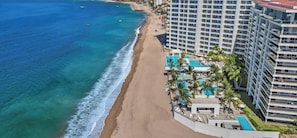 A beachfront hotel with a pool, beach access, and high-rise buildings.