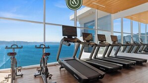 A gym with treadmills and stationary bikes, large windows with a view of the ocean, and a wooden ceiling. - Beatiful Oceanview 1 BR Condo - Pool - Beach (Puerto Vallarta)