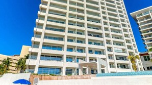A tall, modern hotel with a clear blue sky in the background. - Amazing Studio With Oceanview - Pool - Beach - Gym (Puerto Vallarta)