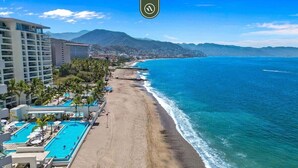A resort with a long sandy beach, a swimming pool, and a view of the ocean and mountains. - Amazing Studio With Oceanview - Pool - Beach - Gym (Puerto Vallarta)