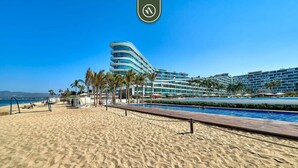 A beachside hotel with a pool, palm trees, and a clear blue sky. - 2BR With Private Balcony - Oceanfront Building (Nuevo Nayarit)