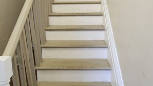 A staircase with white steps and wooden railings, leading to a landing with a framed picture. - Unit 5 The most peaceful and quite area of Schenectady downtown (Schenectady)