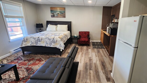 A compact hotel room with a bed, a small seating area, a kitchenette, and a window with blinds. - Unit 5 The most peaceful and quite area of Schenectady downtown (Schenectady)