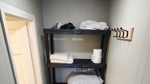 A narrow hallway with a wooden floor, a black shelf unit with folded towels and a laundry basket. - Unit 5 The most peaceful and quite area of Schenectady downtown (Schenectady)
