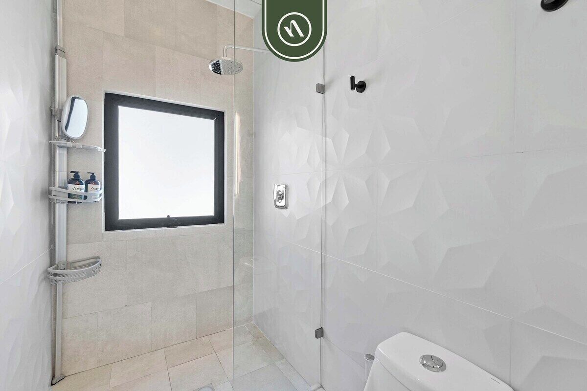 A modern bathroom with a shower, a toilet, and a window.