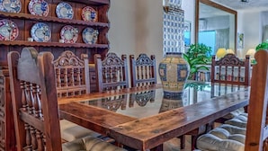 A dining area with a wooden table, chairs, a decorative vase, and a wall of plates.