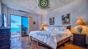A bedroom with a bed, two bedside tables, a nightstand, a window, and a door.