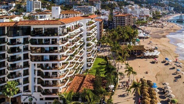 A coastal hotel with multiple balconies, a beach, and a pier.