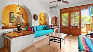 Una habitación con sofá, mesa, lámpara y televisor.