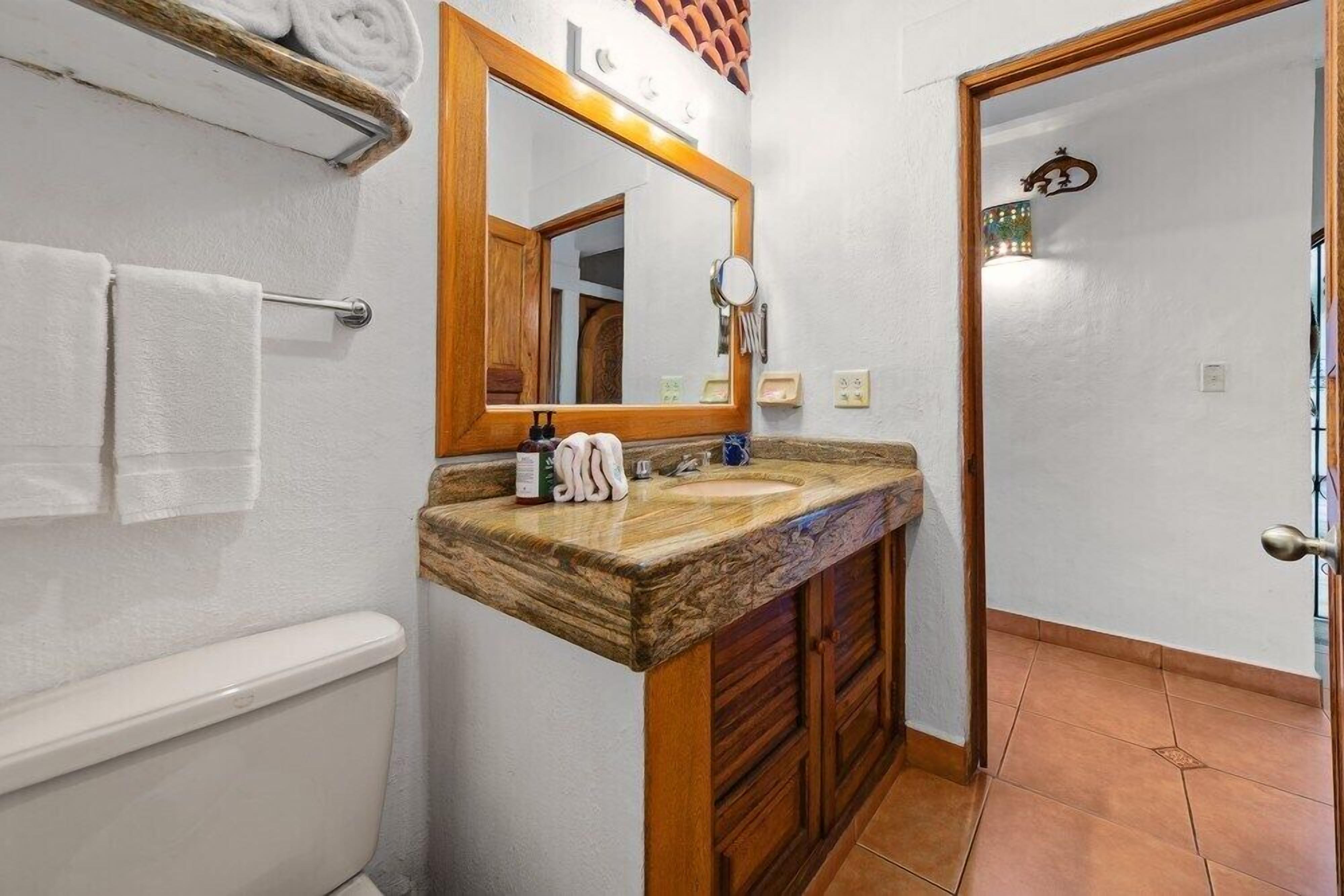 A bathroom with a wooden vanity, a mirror, a towel rack, and a toilet.