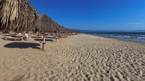 Ein Strand mit Strohdächern und Liegestühlen.