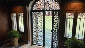A hotel entrance with a decorative wrought iron gate, potted plants, and a view of a courtyard.