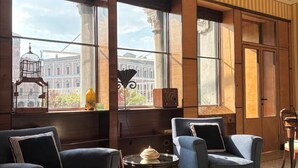 A room with large windows, two armchairs, a small table, and a decorative birdcage.