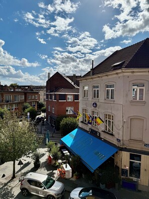 A street view with buildings, a blue awning, and a parked car.