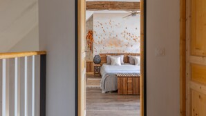 Een slaapkamer met een bed, een houten hoofdeinde en een wand met een bladmotief.