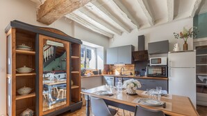 Een moderne keuken met houten kastjes, een eettafel voor vier personen en een trap naar een hoger gelegen verdieping.