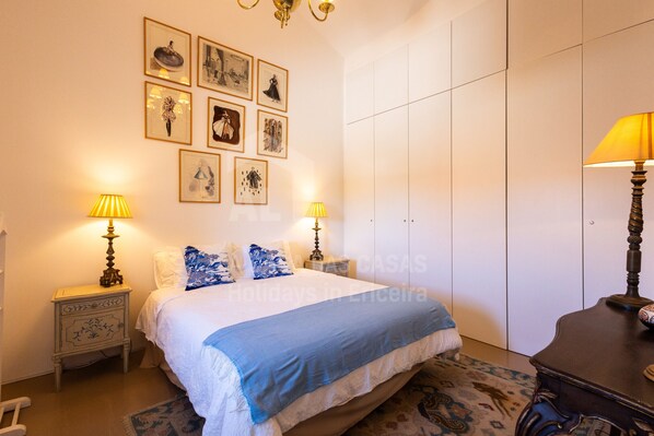 A bedroom with a bed, two bedside tables with lamps, a wardrobe, and a rug.