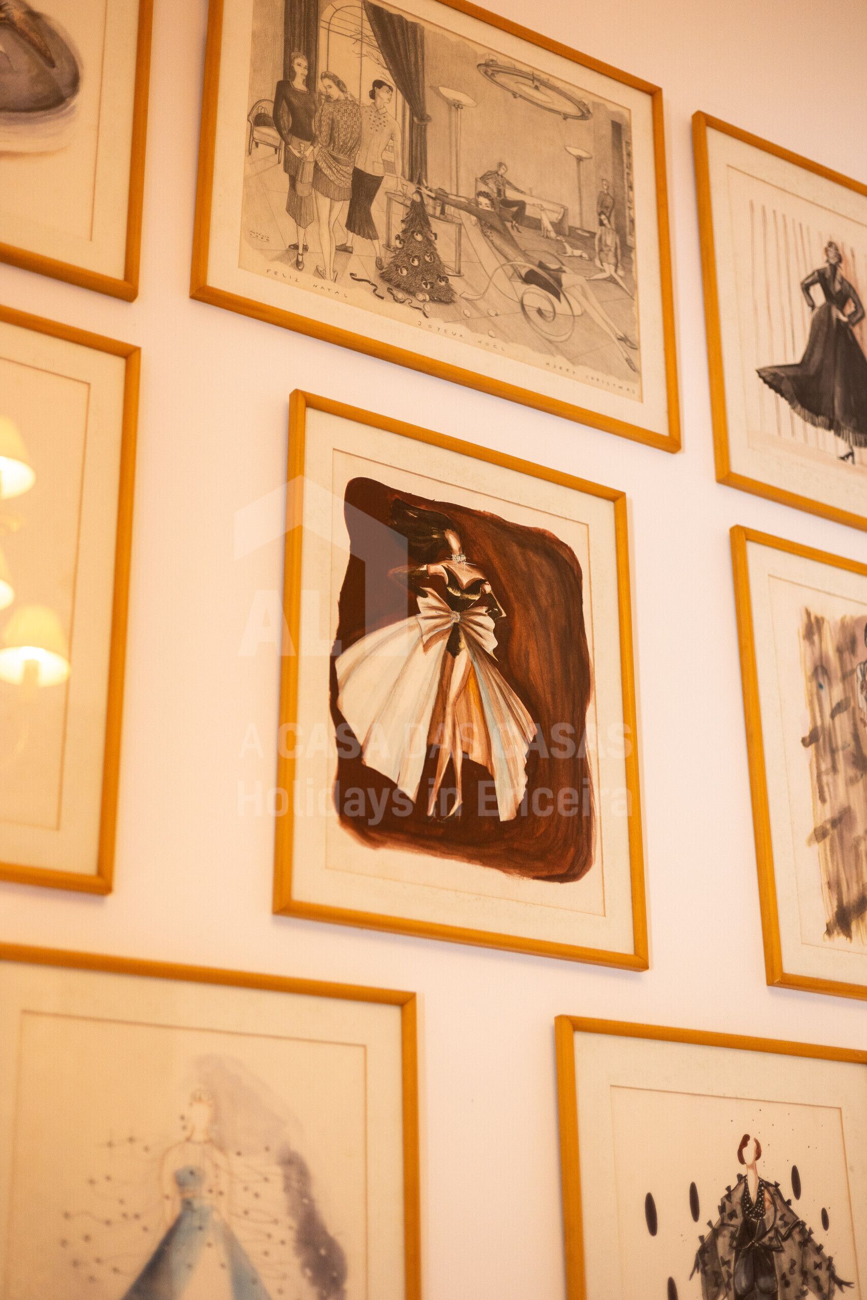Una pared con varias obras de arte enmarcadas, incluyendo retratos y diseños abstractos.
