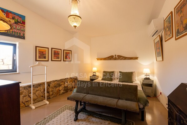 Un dormitorio acogedor con cama, lámparas de noche, una pared de piedra y una lámpara colgante.