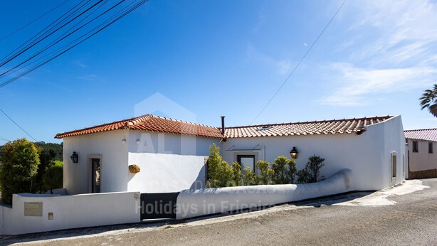 A single-story building with a tiled roof, a small porch, and a white exterior wall.